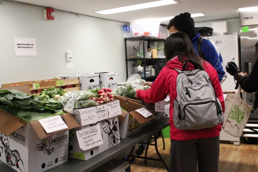 Three Penn students choosing their food items from a selection of fresh produce