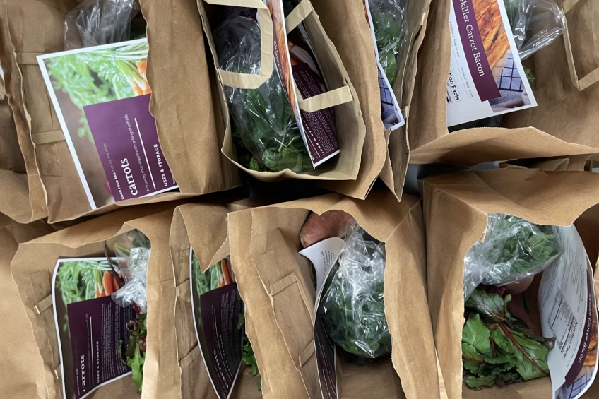 Brown paper bags filled with fresh produce and a recipe